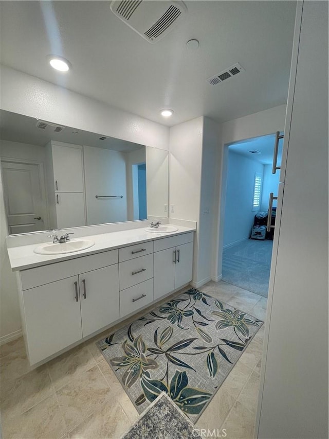 bathroom with double vanity, baseboards, and recessed lighting