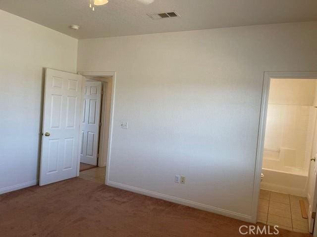 carpeted empty room featuring baseboards and visible vents