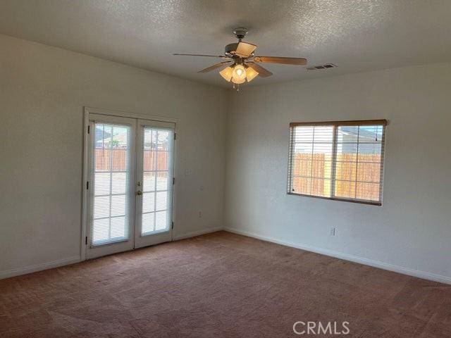 empty room featuring french doors, a ceiling fan, a textured ceiling, visible vents, and carpet