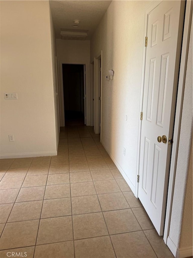 corridor with light tile patterned floors and baseboards
