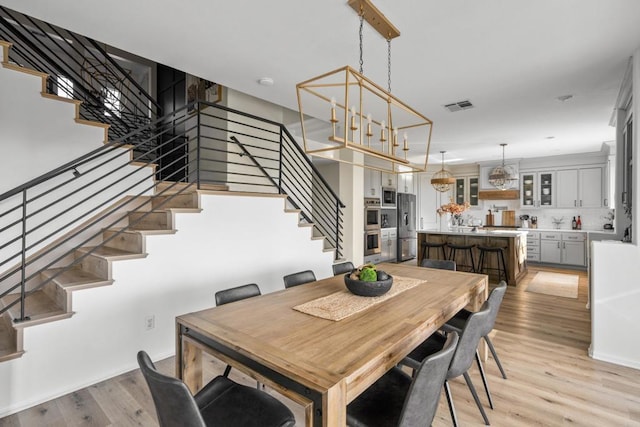 dining room featuring stairs, visible vents, and light wood-type flooring