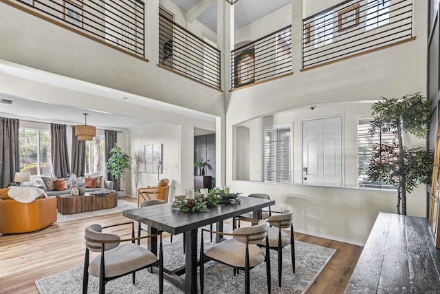 dining space featuring a towering ceiling and wood finished floors