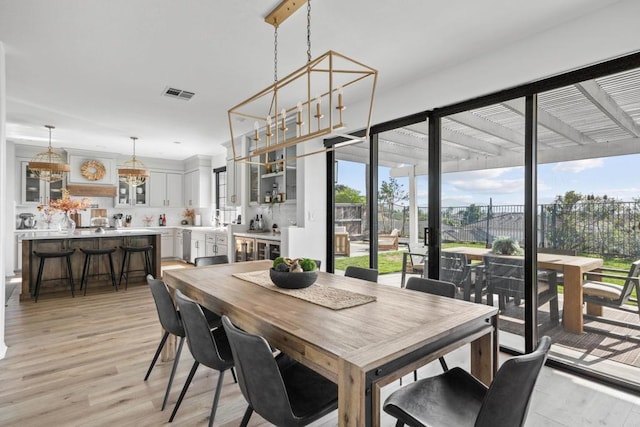 dining area with an inviting chandelier, light wood-style floors, and visible vents