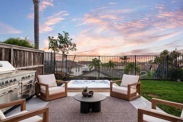 patio terrace at dusk featuring exterior kitchen and a fenced backyard