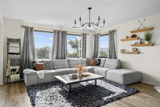 living room featuring baseboards, wood finished floors, and an inviting chandelier