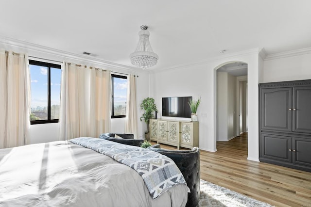 bedroom with crown molding, light wood-type flooring, a chandelier, arched walkways, and visible vents
