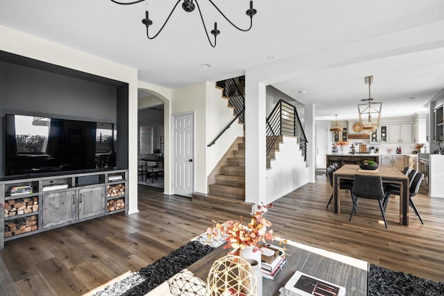 living room with arched walkways, stairs, wood finished floors, and a chandelier