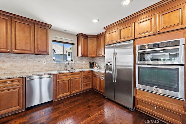 34501 Calle Carmelita, Dana Point, CA 92624 - kitchen with stainless steel appliances, dark wood finished floors, a sink, light stone countertops, and brown cabinets