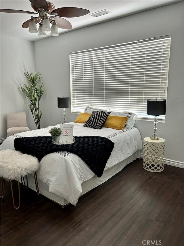 bedroom featuring baseboards, visible vents, wood finished floors, and a ceiling fan