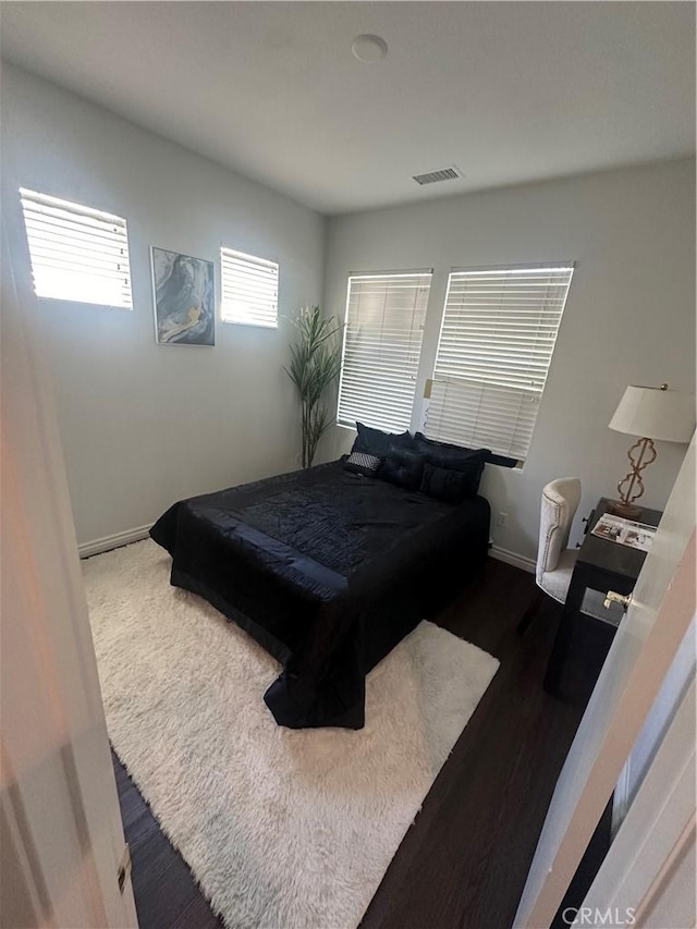 bedroom with wood finished floors, baseboards, and visible vents