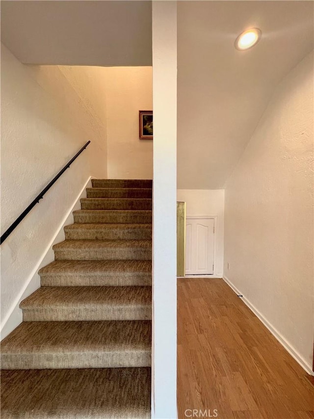 stairs with baseboards, vaulted ceiling, and wood finished floors