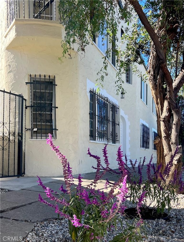 view of property exterior featuring a balcony, stucco siding, and fence