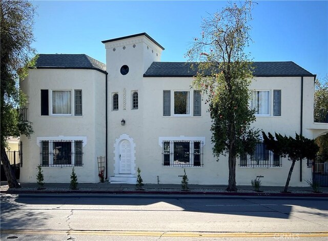 view of front facade with stucco siding and roof with shingles