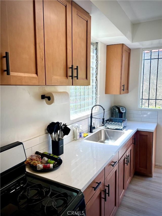 kitchen with light countertops, stainless steel range with gas cooktop, a sink, and tasteful backsplash