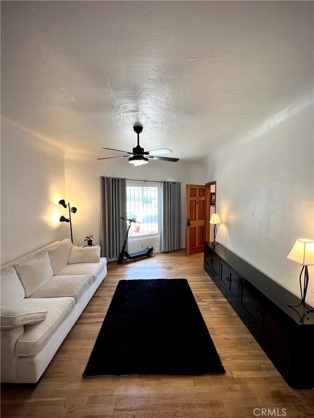 living room featuring a textured ceiling, a ceiling fan, and light wood-type flooring