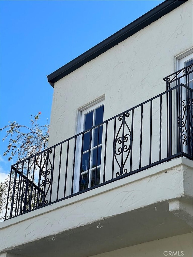 view of side of home featuring a balcony and stucco siding