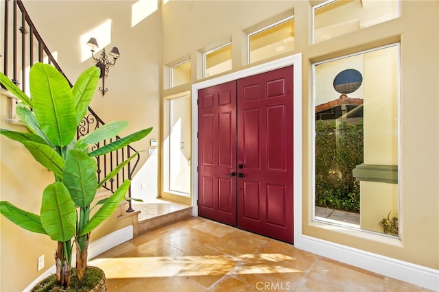 entrance foyer with stairway, a high ceiling, and baseboards