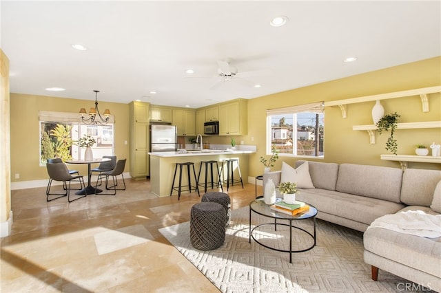 living area featuring ceiling fan with notable chandelier, baseboards, and recessed lighting