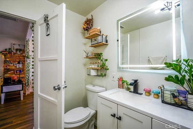201 E Olive St, San Bernardino, CA 92410 - bathroom featuring visible vents, wood finished floors, vanity, and toilet