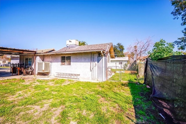 201 E Olive St, San Bernardino, CA 92410 - rear view of house featuring stucco siding, a chimney, fence, and a yard