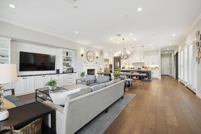 4111 Adriatic St, Oxnard, CA 93035 - living room with crown molding, recessed lighting, dark wood-style flooring, a glass covered fireplace, and built in features