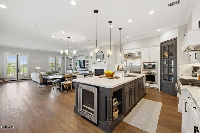 4111 Adriatic St, Oxnard, CA 93035 - kitchen with beverage cooler, built in appliances, open floor plan, crown molding, and white cabinets