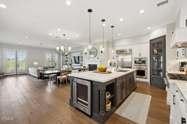 4111 Adriatic St, Oxnard, CA 93035 - kitchen with built in appliances, wine cooler, open floor plan, crown molding, and white cabinetry
