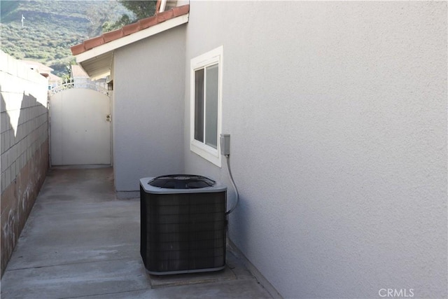 exterior details featuring cooling unit, stucco siding, fence, and a gate