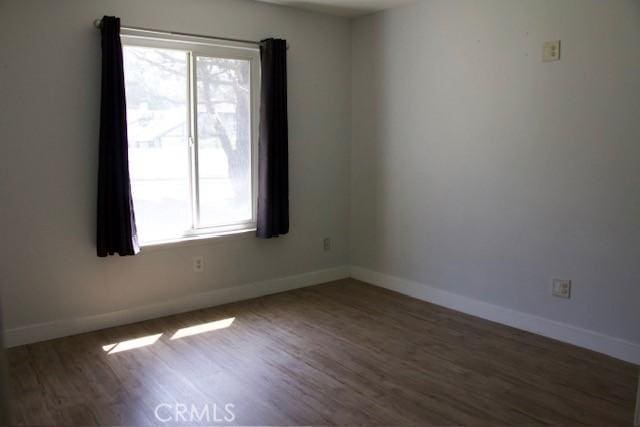 unfurnished room with a wealth of natural light, baseboards, and wood finished floors