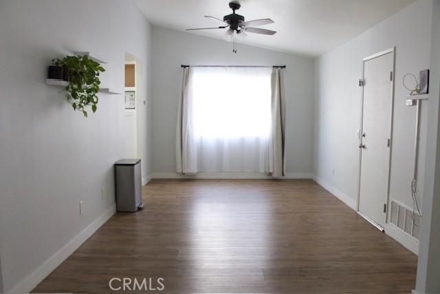 interior space with visible vents, baseboards, ceiling fan, wood finished floors, and lofted ceiling