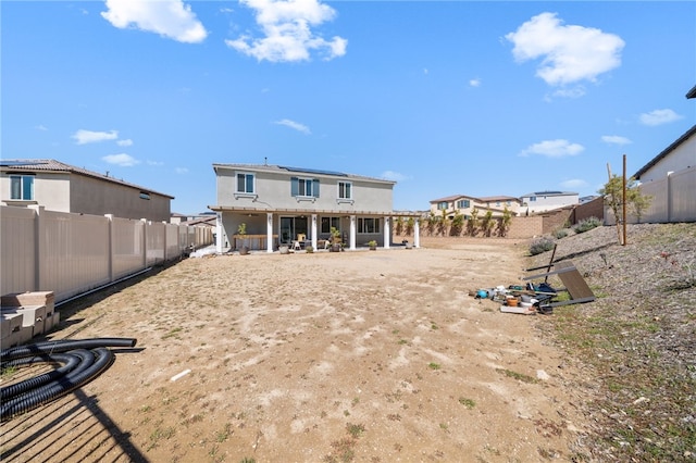 back of property with solar panels, a fenced backyard, and a patio area