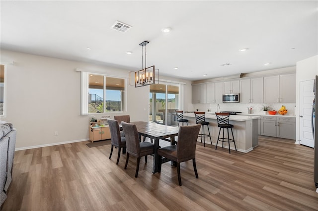dining room with visible vents, baseboards, light wood finished floors, an inviting chandelier, and recessed lighting