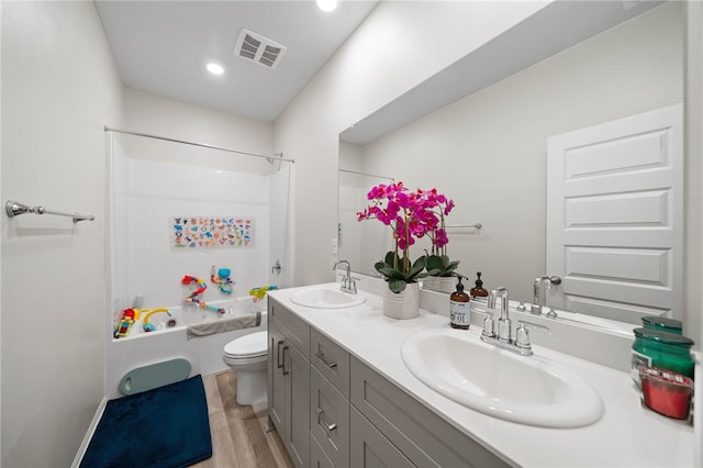 bathroom featuring a sink, double vanity, toilet, and wood finished floors