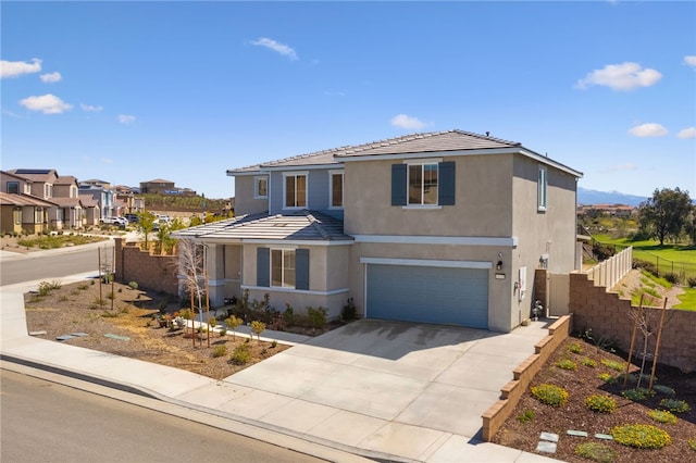 traditional-style home featuring a residential view, a garage, fence, concrete driveway, and stucco siding