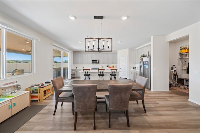 dining space with recessed lighting, light wood-style flooring, and a chandelier