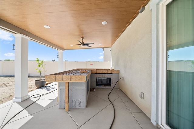 view of patio featuring an outdoor bar, ceiling fan, and fence