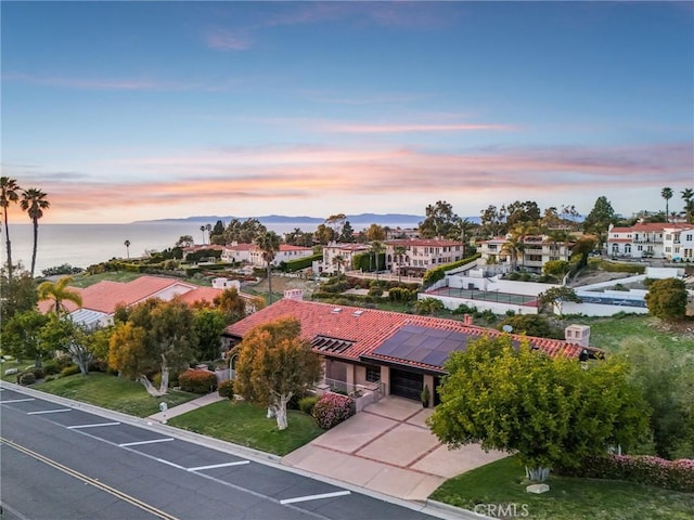 aerial view at dusk featuring a residential view and a water view