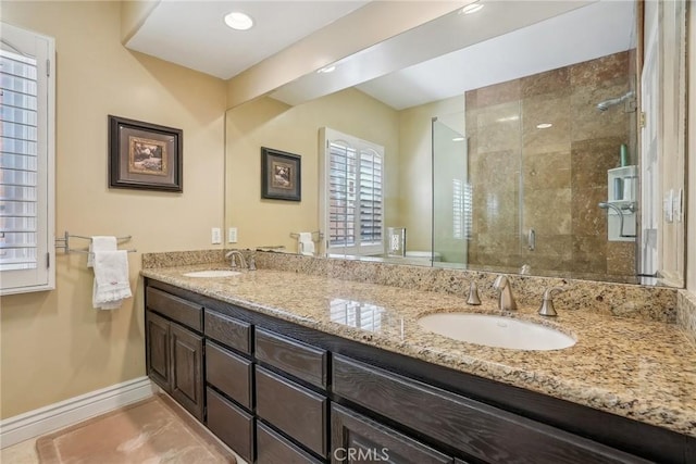 full bath featuring double vanity, a shower stall, baseboards, and a sink