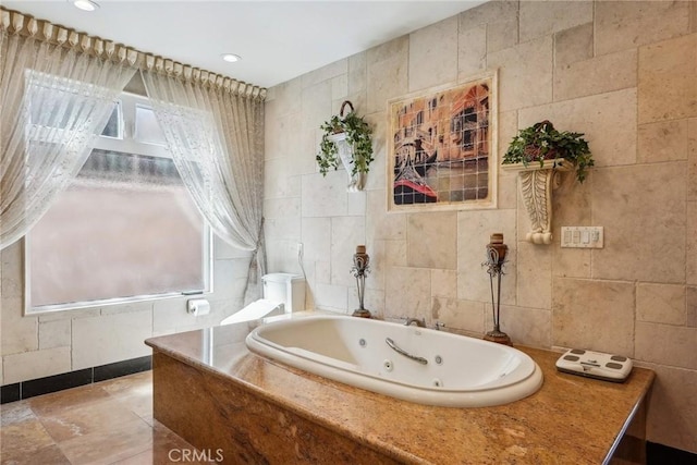 full bath with tile walls, recessed lighting, and a tub with jets