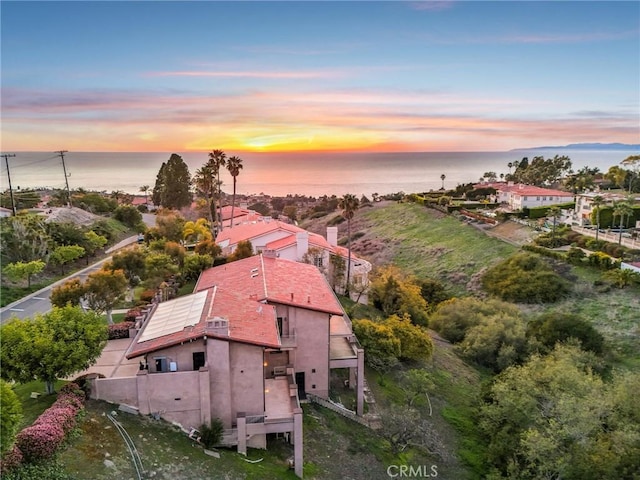 aerial view at dusk featuring a water view