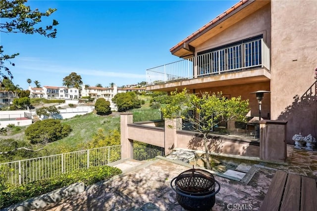 view of patio with fence and a balcony