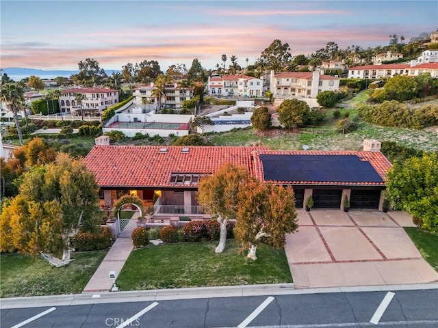 view of front facade featuring a front lawn, a tiled roof, a residential view, and solar panels