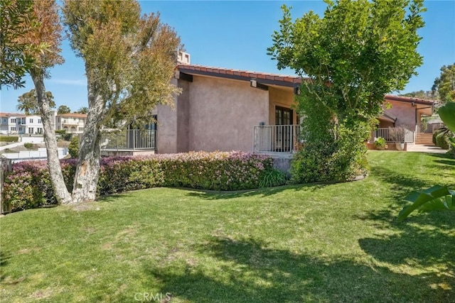 exterior space with a lawn, a tiled roof, and stucco siding