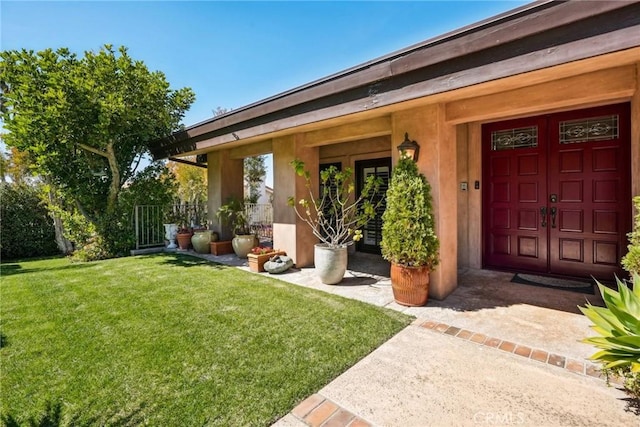view of exterior entry featuring stucco siding and a yard