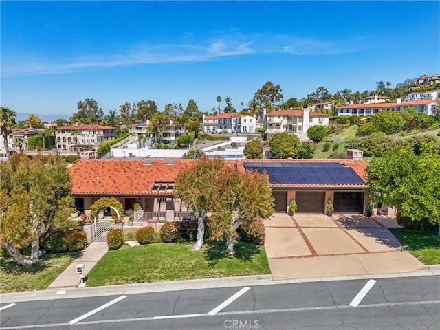 view of front facade featuring a tile roof, a front yard, concrete driveway, solar panels, and stucco siding
