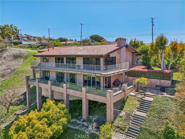back of property with a chimney, a balcony, and stucco siding