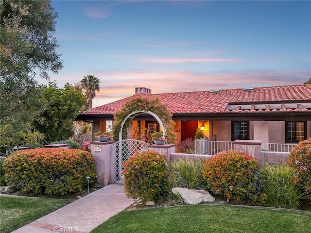 view of front facade with stucco siding, a gate, a tiled roof, and fence private yard