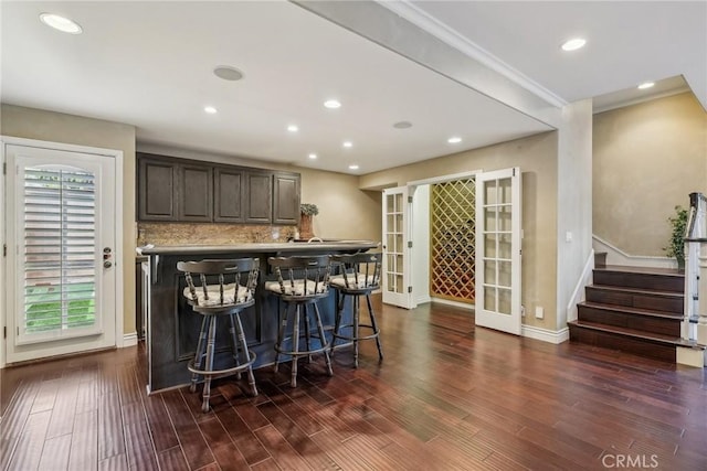 bar featuring baseboards, backsplash, dark wood-style floors, stairway, and french doors