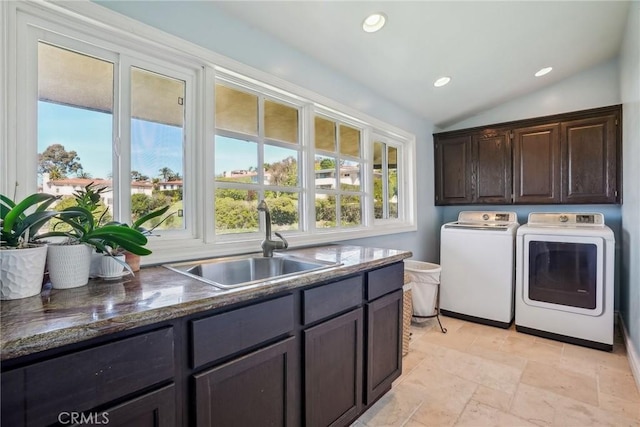 clothes washing area featuring a healthy amount of sunlight, washer and clothes dryer, cabinet space, and a sink