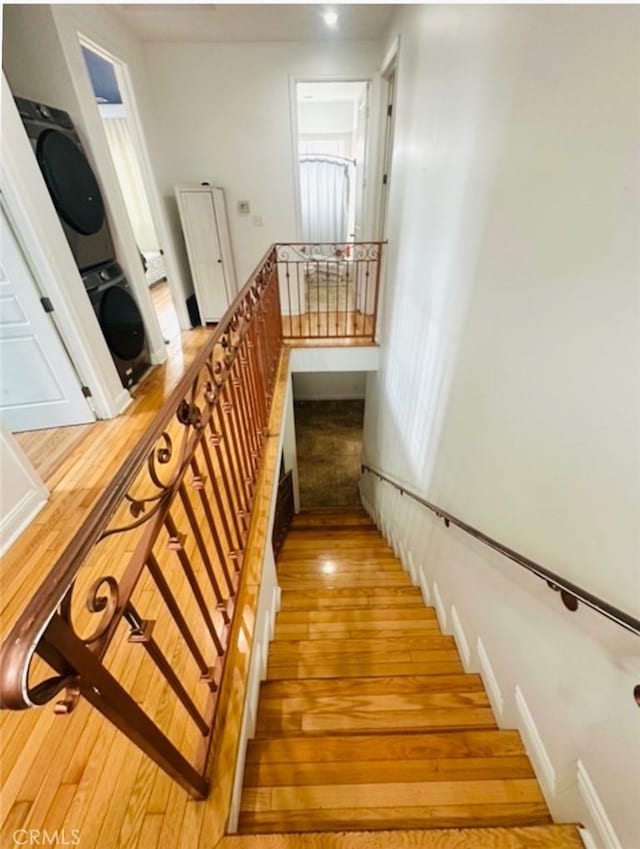 staircase featuring hardwood / wood-style floors and stacked washer / dryer